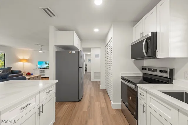 a kitchen with a refrigerator a sink and a stove top oven with wooden floor