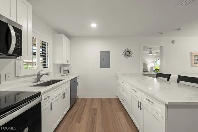 a kitchen with a sink dishwasher stove and white cabinets