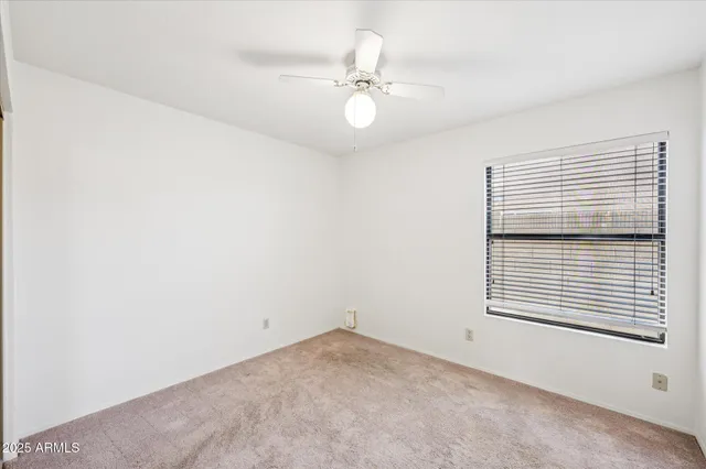 an empty room with a window and a fan