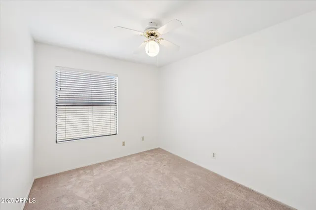 an empty room with a chandelier fan and windows