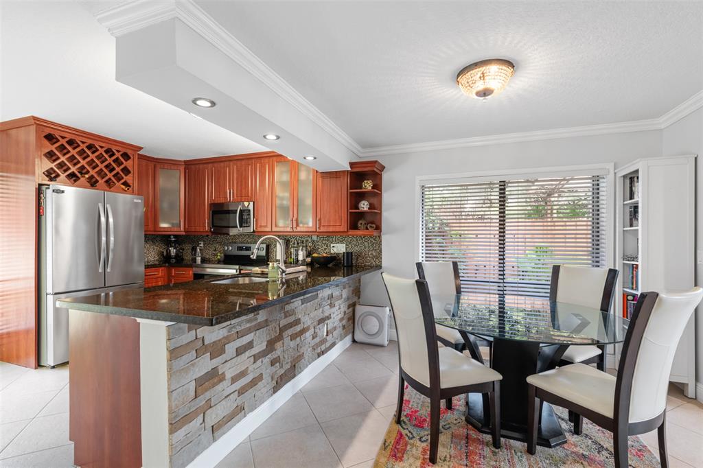 11927 Southwest 13th Court Davie, FL 33325 - Photo 16 of 41 a kitchen with stainless steel appliances granite countertop a stove a refrigerator a kitchen island a table and chairs