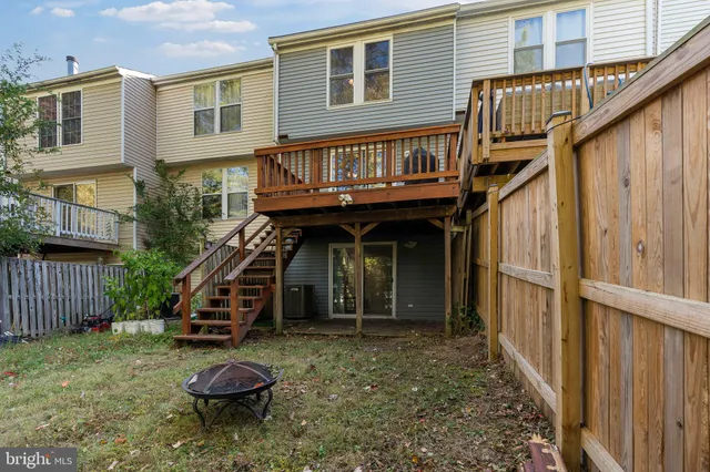 a view of small house with wooden deck and furniture