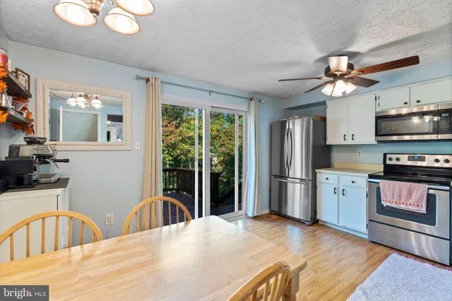 a kitchen with stainless steel appliances granite countertop a refrigerator a stove a sink dishwasher a dining table and chairs with wooden floor