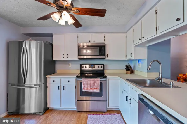 a kitchen with stainless steel appliances granite countertop a refrigerator a stove a sink and dishwasher with wooden floor