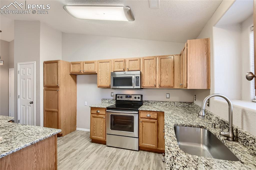3780 Riviera Grove, Unit 204 Colorado Springs, CO 80922 - Photo 17 of 33 a kitchen with stainless steel appliances granite countertop a stove a sink and a refrigerator