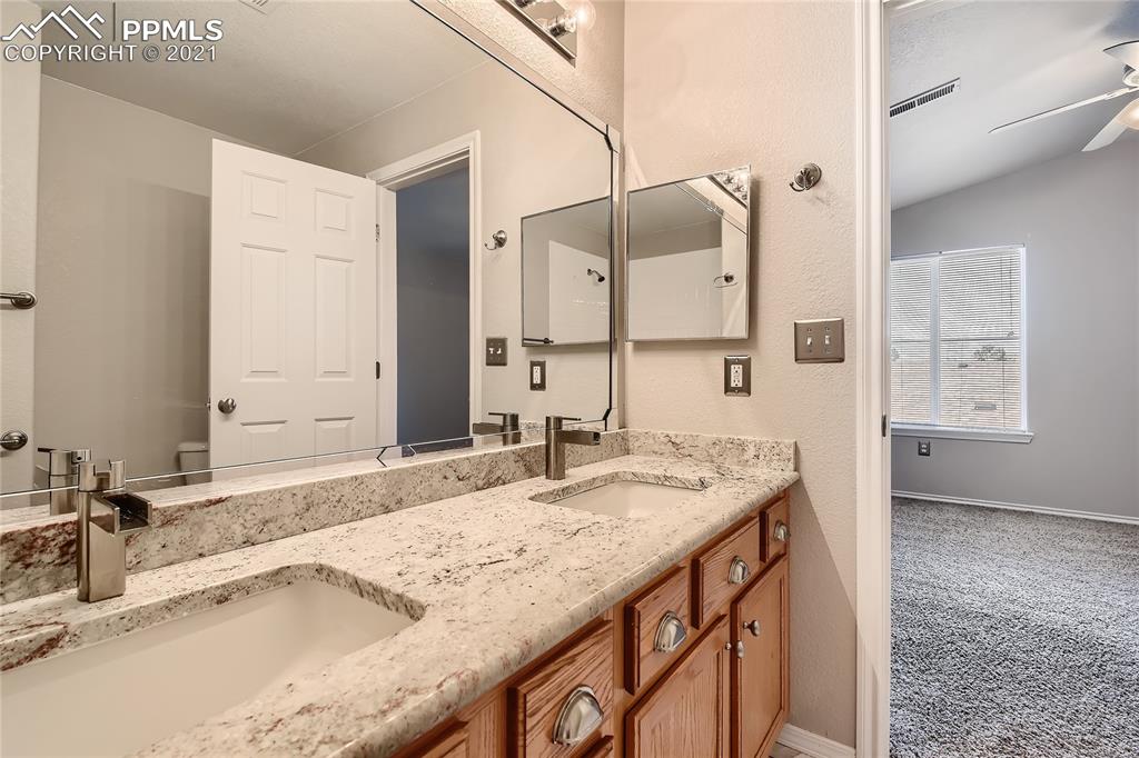 3780 Riviera Grove, Unit 204 Colorado Springs, CO 80922 - Photo 24 of 33 a bathroom with a granite countertop sink and a mirror