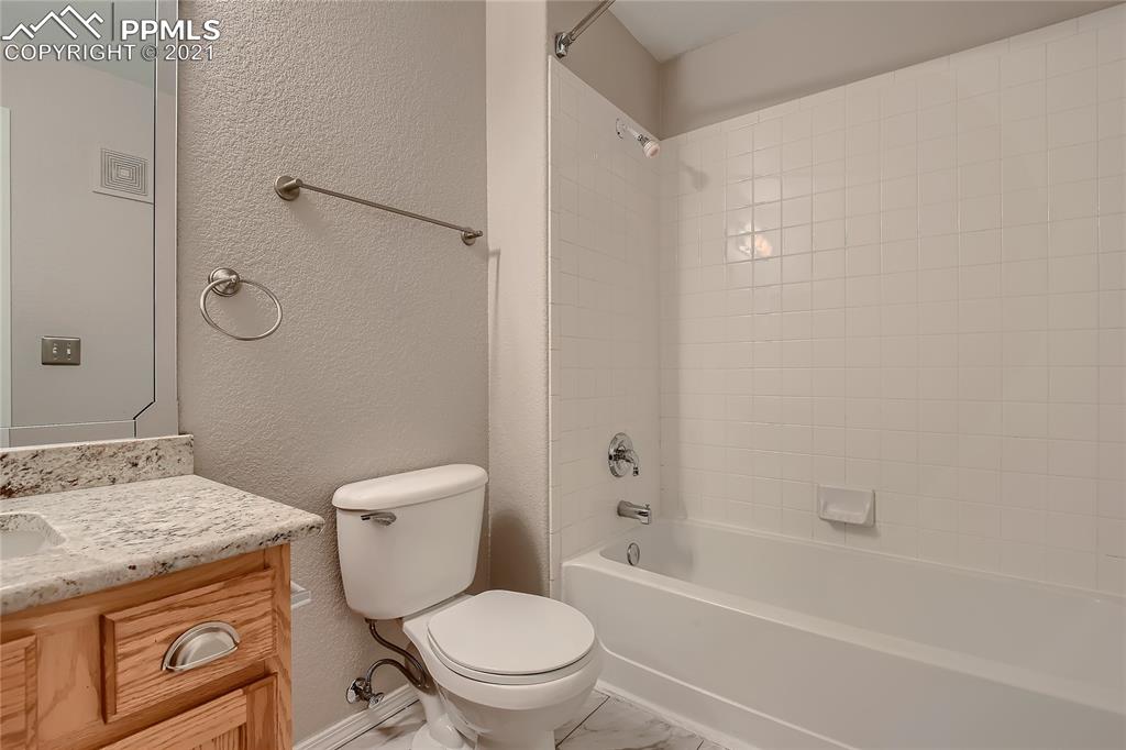 3780 Riviera Grove, Unit 204 Colorado Springs, CO 80922 - Photo 30 of 33 a bathroom with a granite countertop toilet a sink and a bathtub