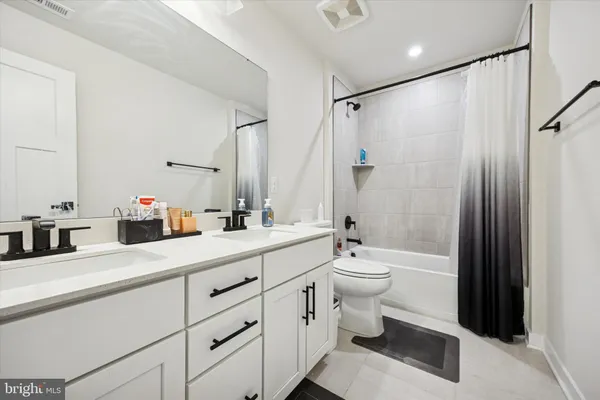 a bathroom with a double vanity sink toilet mirror and shower