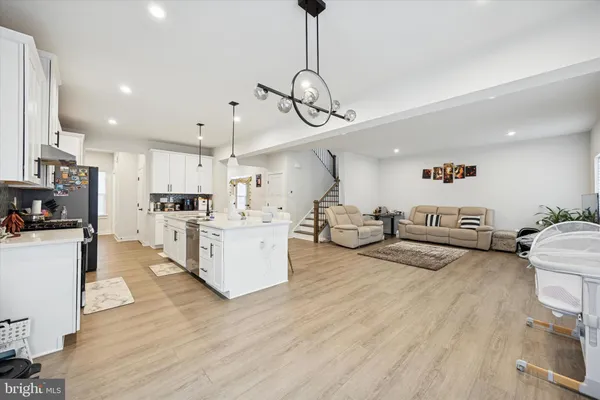 a living room with furniture kitchen view and a wooden floor
