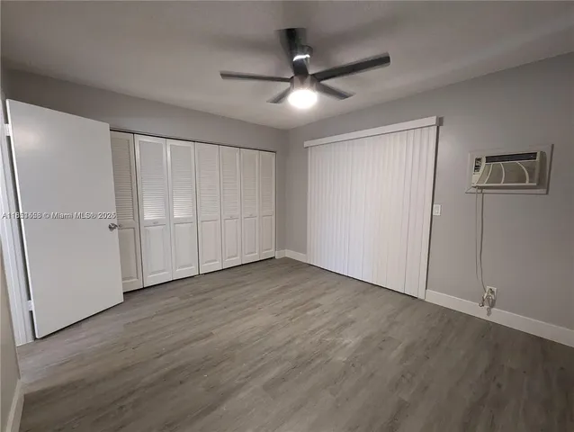 an empty room with wooden floor closet and windows
