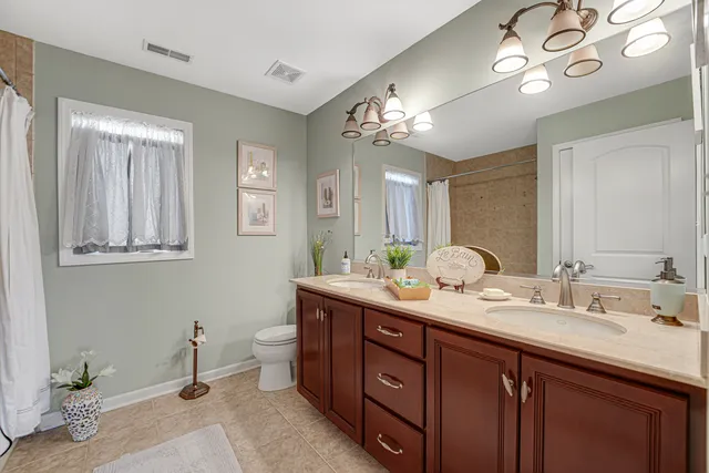 a spacious bathroom with double vanity a mirror and a light fixture