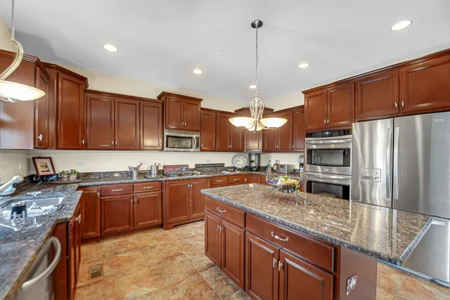 a kitchen with stainless steel appliances granite countertop a sink a stove and a refrigerator