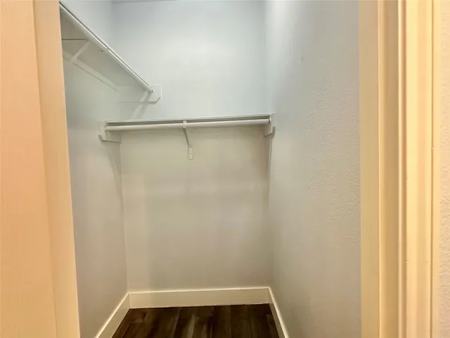 an empty room with wooden floor closet and windows