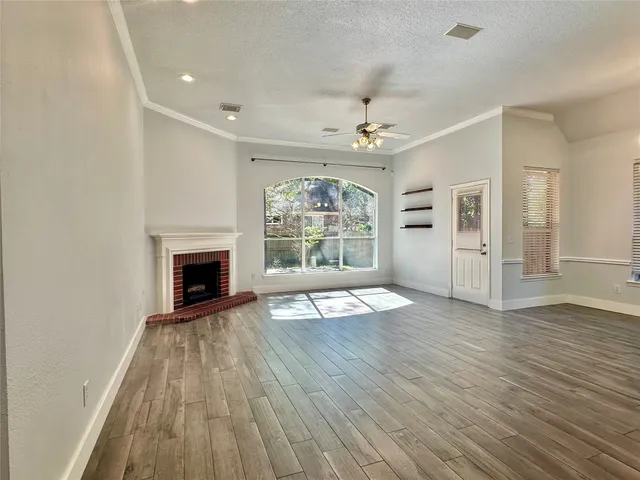 an empty room with wooden floor fireplace and windows