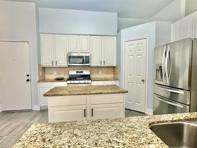 a kitchen with granite countertop white cabinets and stainless steel appliances