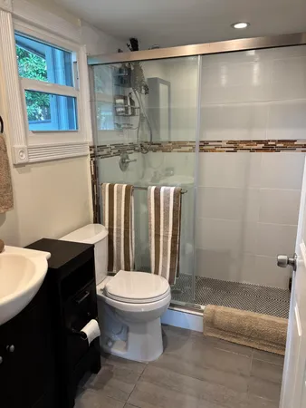 a bathroom with a granite countertop bathtub shower sink vanity and toilet