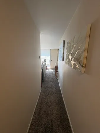 a view of a hallway with wooden floor and a living room