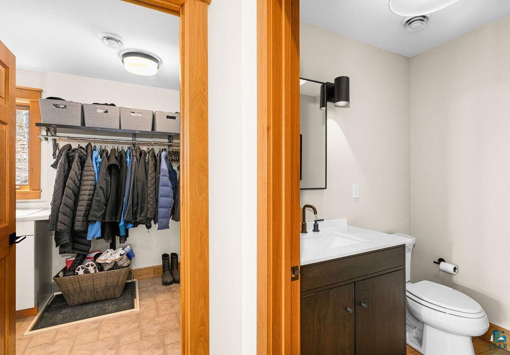 4856 Kingston Street Duluth, MN 55804 - Photo 17 of 88 Functional mudroom featuring tile flooring and built-in shelving, with a powder room offering a dark wood-finish vanity with white countertop and a matte black faucet