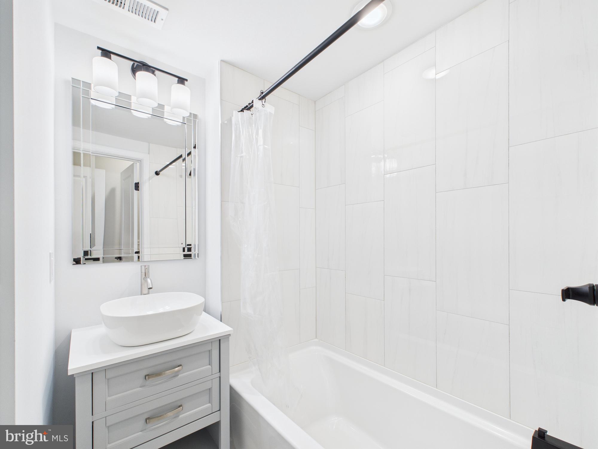1320 Grove Street, Unit 2 Philadelphia, PA 19146 - Photo 2 of 15 a bathroom with a sink a mirror and a bathtub