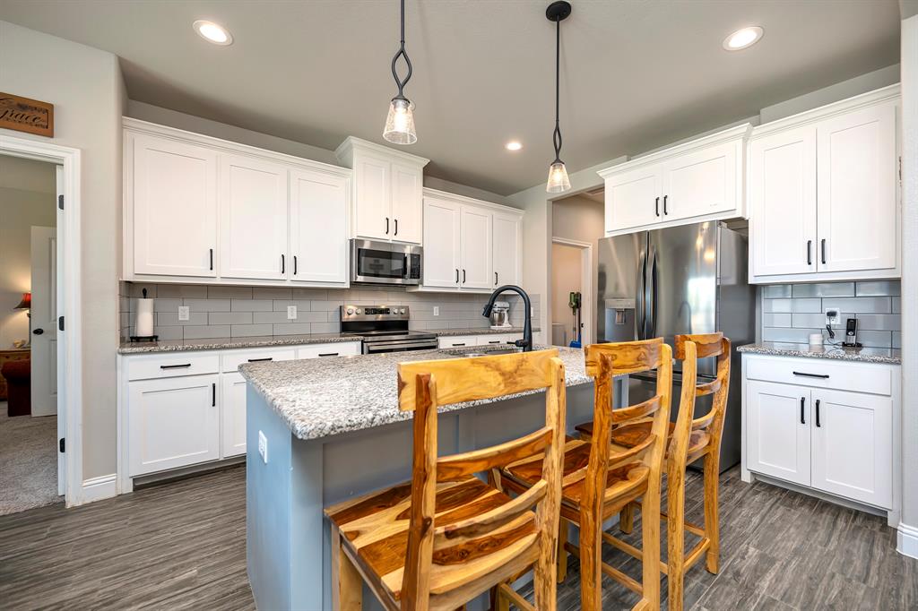 917 East 3rd Street Springtown, TX 76082 - Photo 3 of 32 Farmhouse kitchen with massive island, shaker cabinets, stainless appliances and granite counters!