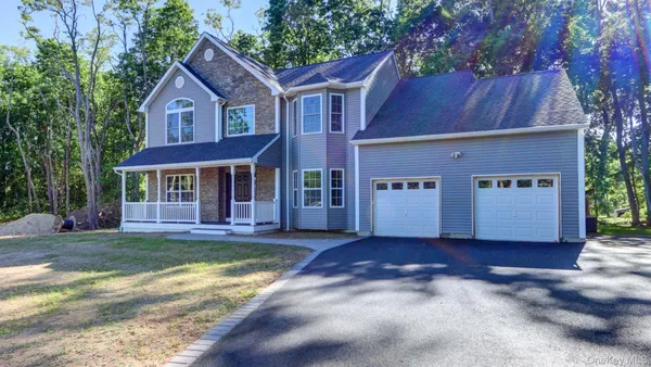 a view of a house with a yard plants and large tree