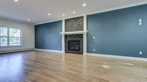 an empty room with wooden floor fireplace and windows