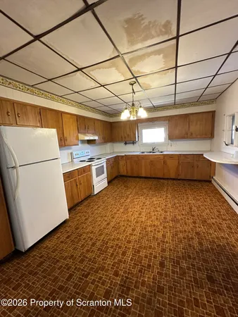 a kitchen with kitchen island a sink wooden floor and white stainless steel appliances