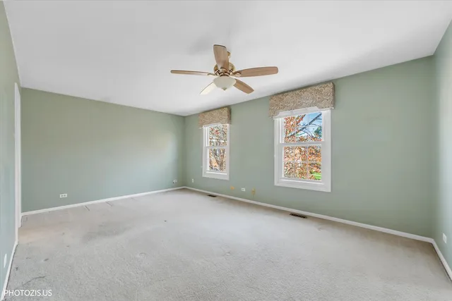 an empty room with windows and fan