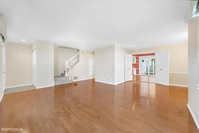 a view of an empty room with wooden floor and kitchen