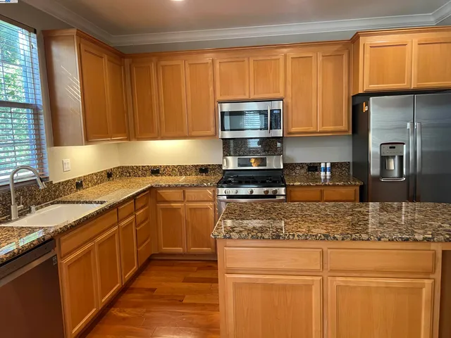 a kitchen with stainless steel appliances granite countertop a sink stove microwave and refrigerator