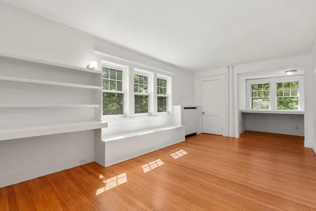 a view of an empty room with a window and wooden floor