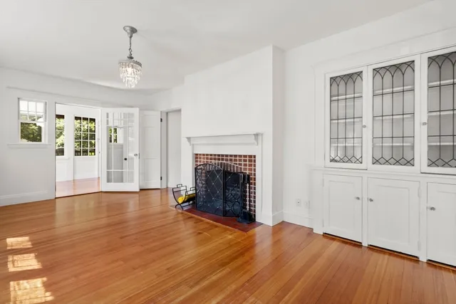 a view of an empty room with wooden floor fireplace and a window