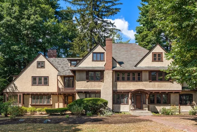 a view of a white house with a large tree and plants