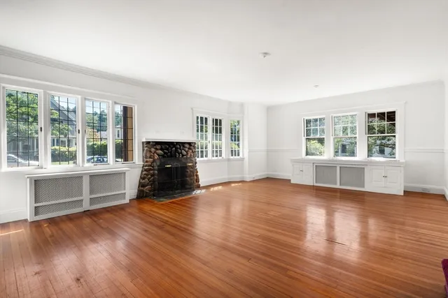 a view of empty room with wooden floor and fireplace