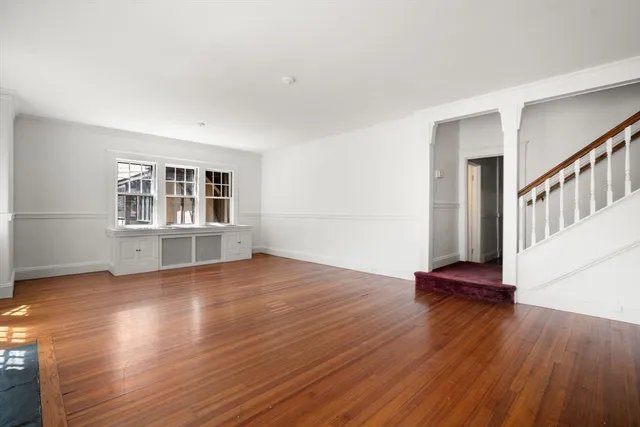 a view of an empty room with wooden floor and windows