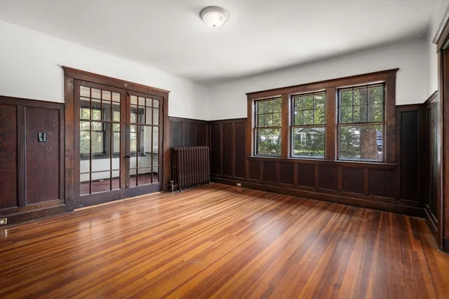 a view of an empty room with wooden floor and a window