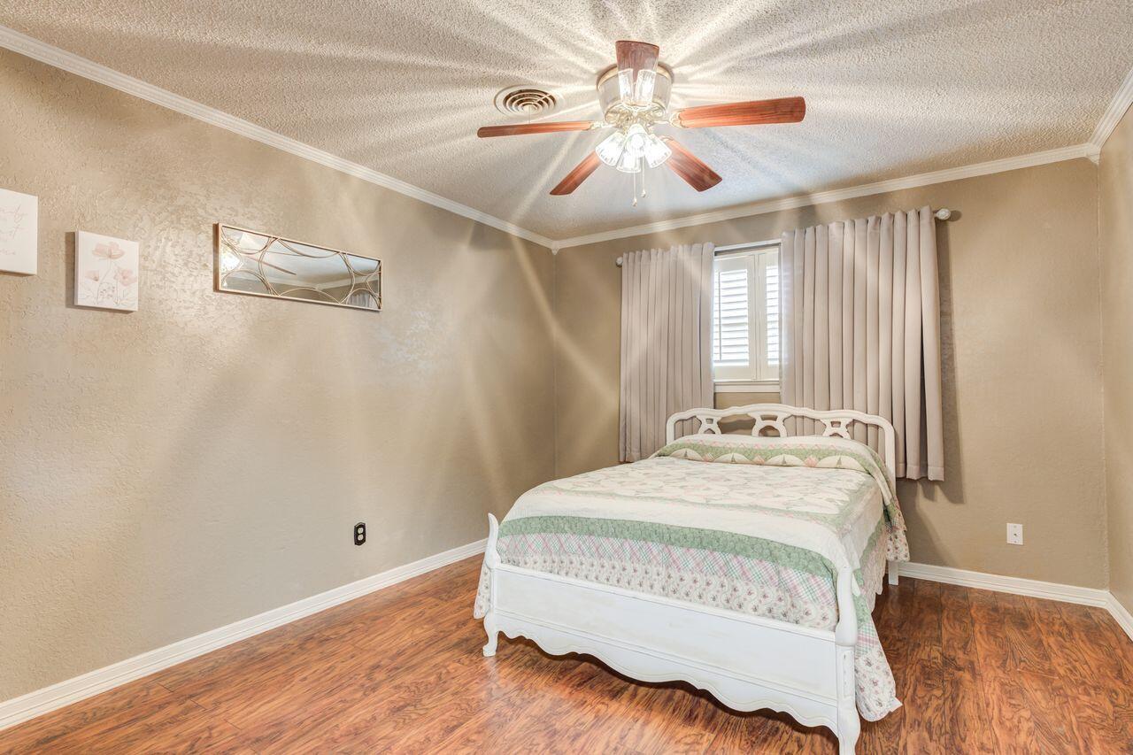4904 18th Street Lubbock, TX 79416 - Photo 28 of 39 a bedroom with a large bed and a chandelier