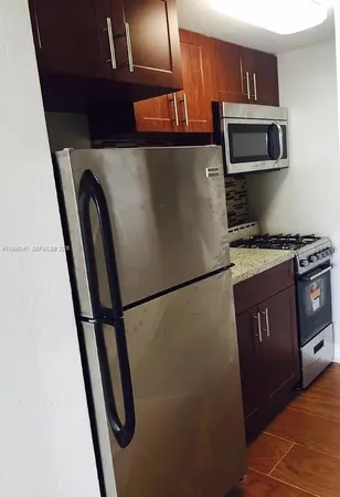 a kitchen with stainless steel appliances granite countertop a refrigerator a stove a microwave a sink and dishwasher