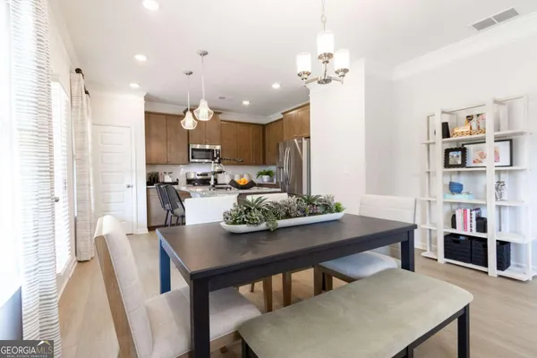 a kitchen with stainless steel appliances a dining table chairs and a refrigerator