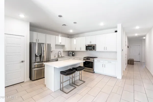 a kitchen with stainless steel appliances a stove a sink a stove a refrigerator with white cabinets and table