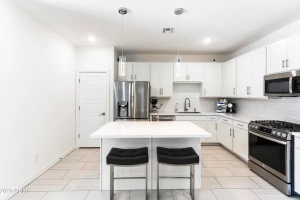 a large white kitchen with a table and chairs
