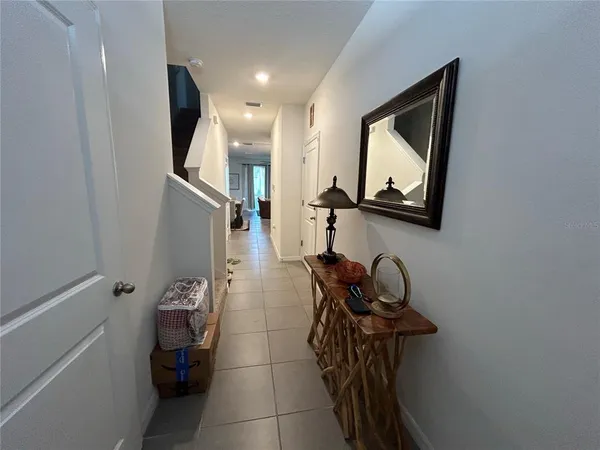 a hallway with a view of bathroom with mirror on the wall