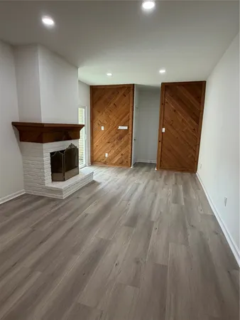 a view of an empty room with wooden floor and a fireplace