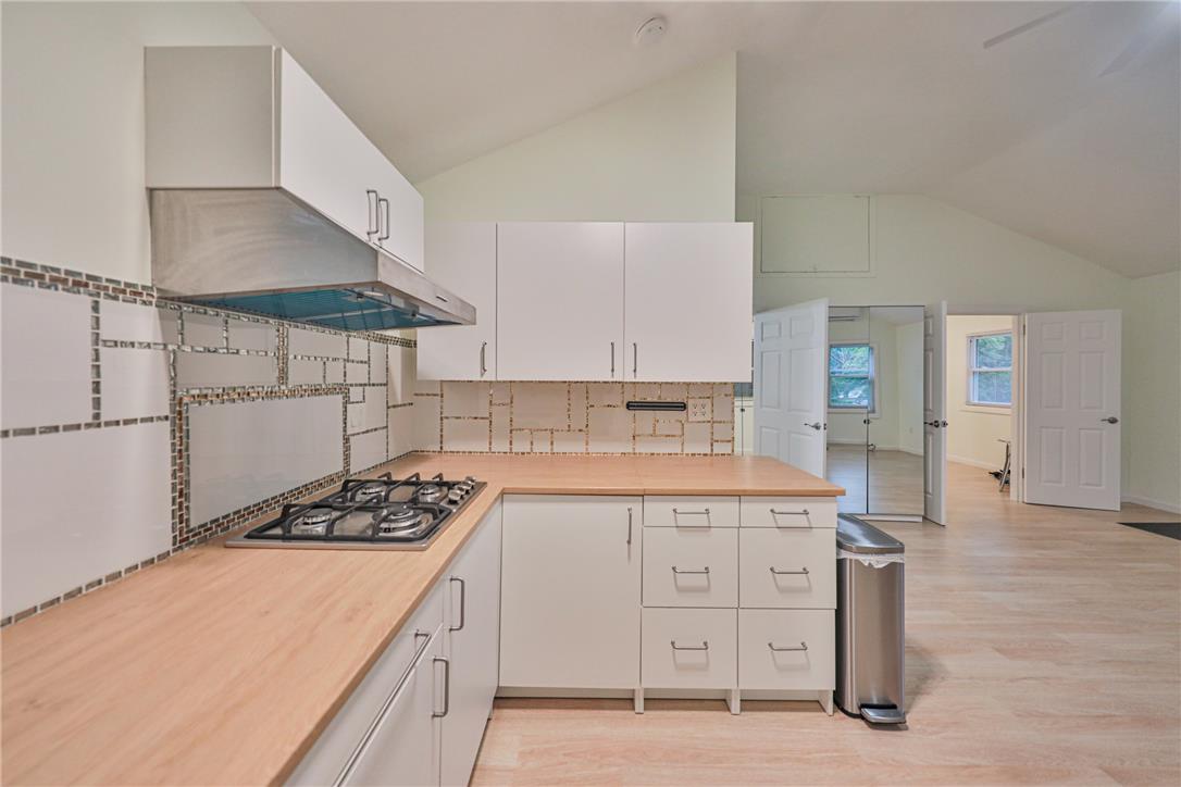 5599 Minks Pond Road Bushkill, PA 18324 - Photo 16 of 64 Modern kitchen with sleek white cabinetry and natural wood countertops perfect for culinary endeavors.