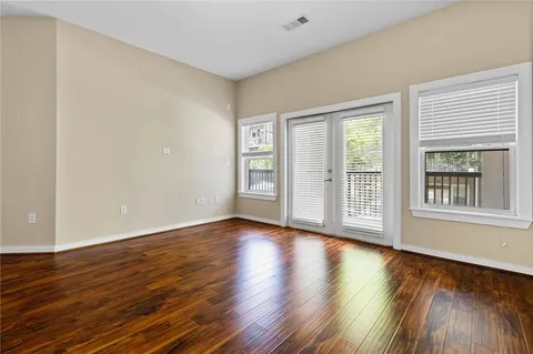 a view of an empty room with wooden floor and a window