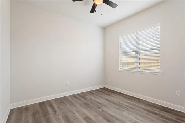 an empty room with a window and ceiling fan