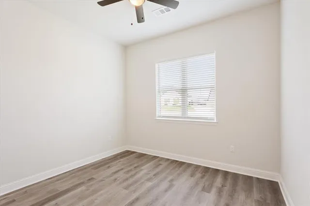 an empty room with a window and a ceiling fan