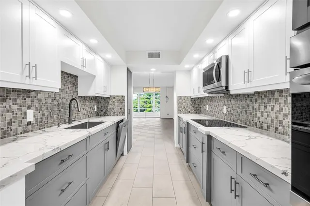 a large kitchen with stainless steel appliances granite countertop a sink and dishwasher a stove top oven with white cabinets