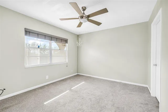an empty room with a window and a ceiling fan