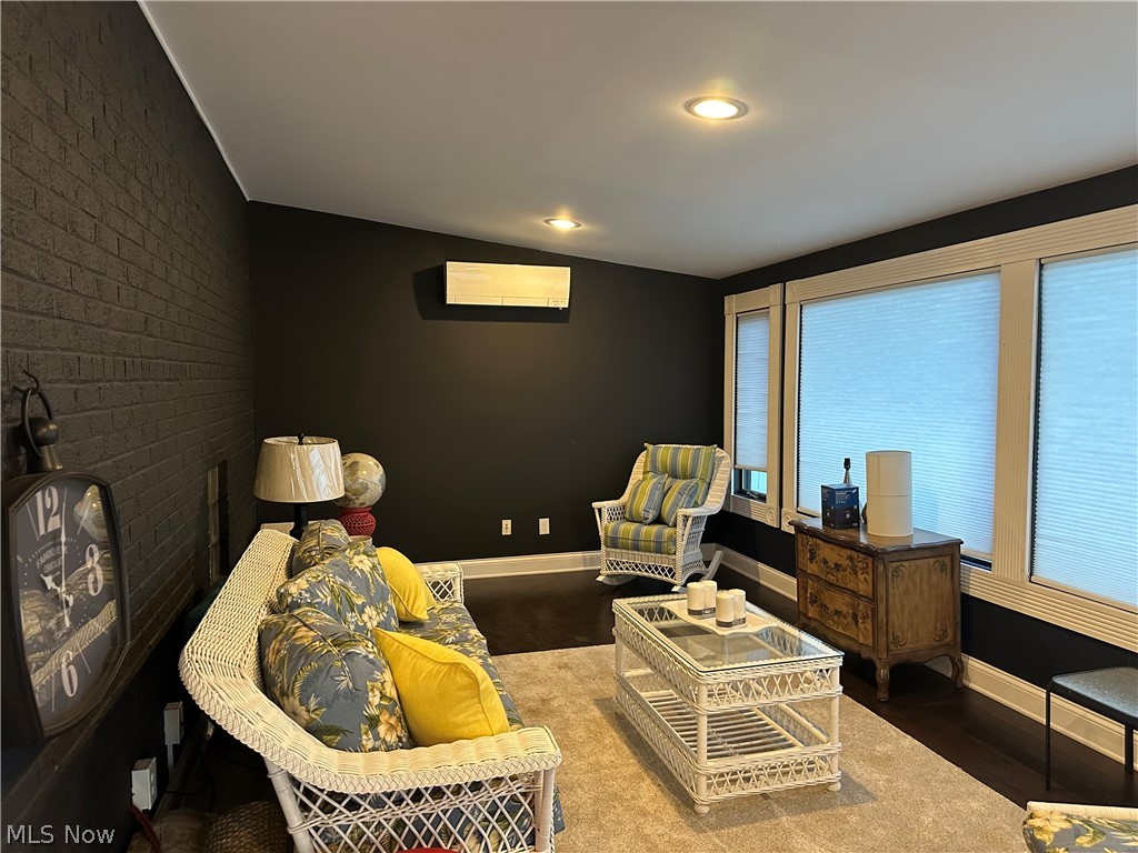 Sitting room featuring brick wall, recessed lighting, dark wood-type flooring, vaulted ceiling, and an accent wall